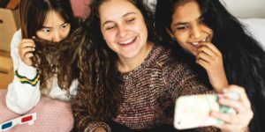 Foto bij veelgestelde vraag hoe stimuleer je prosociaal gedrag. Drie meisjes maken een selfie