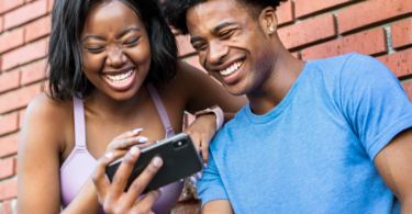 Foto bij artikel over online sociale normen. Twee jonge mensen lachen om wat ze zien op smartphone