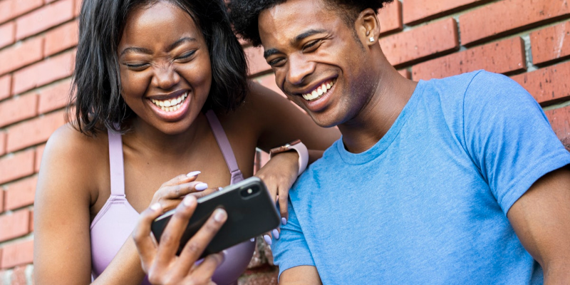 Foto bij artikel over online sociale normen. Twee jonge mensen lachen om wat ze zien op smartphone